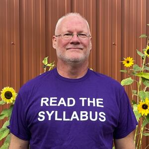 Robb McKay with t-shirt that reads "Read the Syllabus"